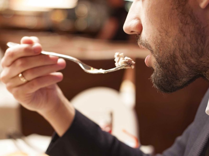 Mann som spiser mat i restauranten